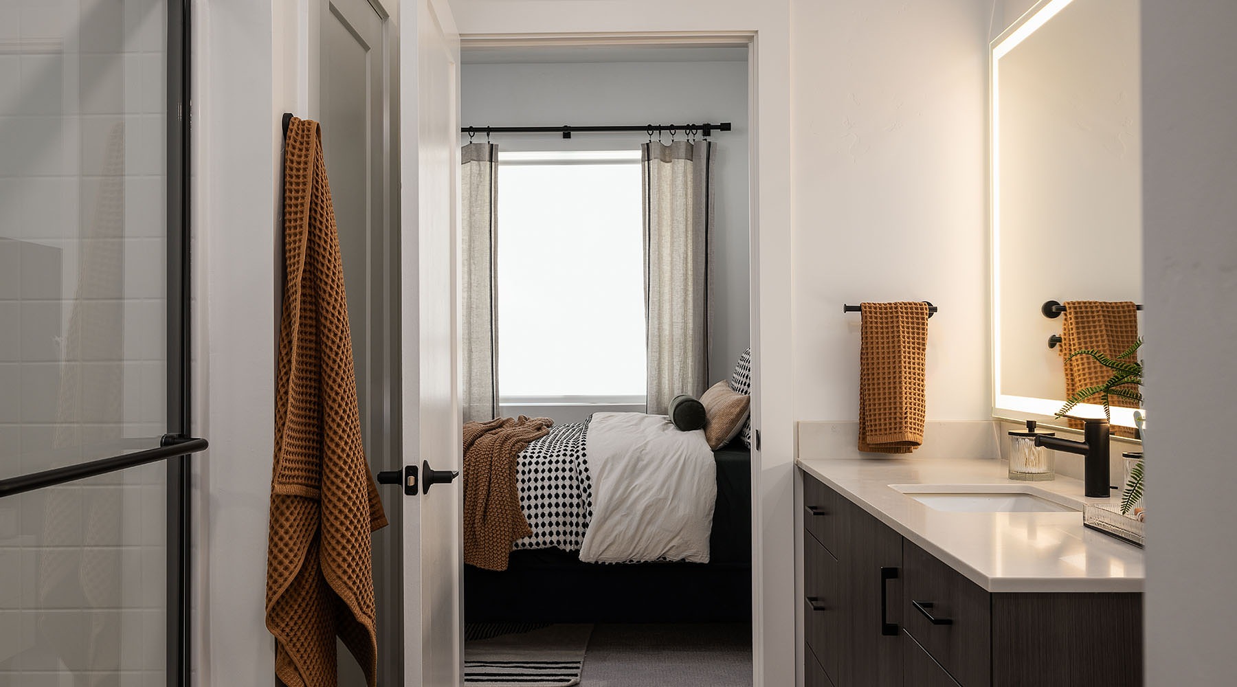 Spacious Bathrooms with Everything You Need a bathroom with a sing and mirror with view of a bedroom